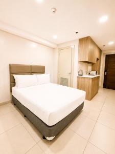 a bedroom with a large white bed and a kitchen at Milton Hotel Makati in Manila