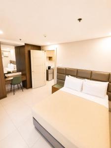 a bedroom with a large bed and a kitchen at Milton Hotel Makati in Manila