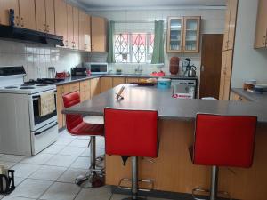 a kitchen with a counter and red chairs in it at The Corner Lounge - Lenasia in Lenasia
