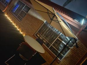 an umbrella and chairs in front of a building at The Corner Lounge - Lenasia in Lenasia