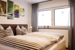 a bedroom with a bed with striped sheets and a window at Kapellenblick Auszeit mit Ausblick in Heroldstatt