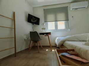 a living room with a bed and a desk with a chair at Little Kristi in Palaiókastron