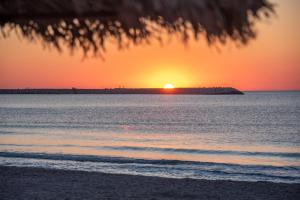 a sunset on the beach with the sun setting over the ocean at Mera Holiday Resort in Venus