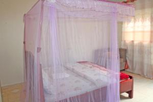 a bedroom with a canopy bed with pink curtains at Kolstar Hotel SMC Ltd in Ogwam