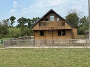 a wooden house with a fence in front of it at Owls Nest in Larling