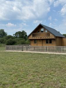 a wooden house with a fence in front of a field at Owls Nest in Larling +6 photos