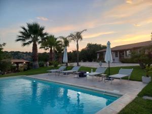 a pool with chairs and umbrellas in a yard at Villa Concita in Noto