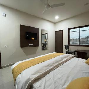 a bedroom with a bed and a tv on the wall at Wellawing Regency Samrala Chownk in Ludhiana