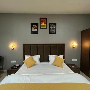 a bedroom with a large white bed with yellow pillows at Wellawing Regency Samrala Chownk in Ludhiana +2 photos