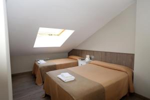 ein kleines Zimmer mit zwei Betten und einem Dachfenster in der Unterkunft Hotel El Balcón in Avilés