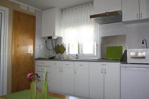 a kitchen with white cabinets and a sink and a window at Valbom by Campigir in Sesimbra