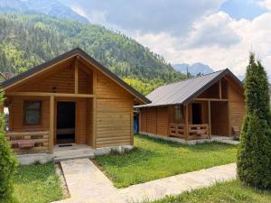 two wooden cabins with mountains in the background at Valbone Two E in Valbonë