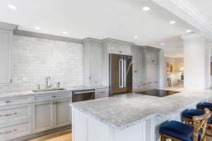a kitchen with white cabinets and a large marble counter top at Two Bedroom Bayfront Condo with Water Views in Naples