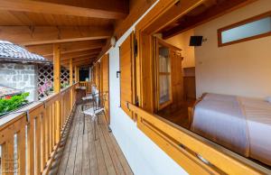 ein Balkon einer Blockhütte mit einem Bett und einem Fenster in der Unterkunft Dependance GRIMANI in Ampezzo