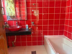 a red tiled bathroom with a sink and a tub at Nilayam guest house in Patna +29 photos