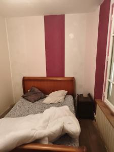 a bed in a room with a red and white wall at Chambre pèlerinage in Saint-Hilaire-la-Palud