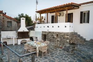 a patio with a table and a fireplace with birds on it at Joanna's House in Koumaradaíoi +27 photos