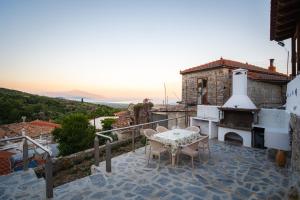 a balcony of a house with a table and a fireplace at Joanna's House in Koumaradaíoi