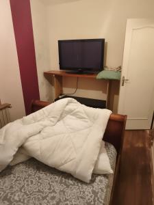 a bedroom with a bed and a desk with a television at Chambre pèlerinage in Saint-Hilaire-la-Palud