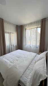 a large white bed in a bedroom with windows at Guest House Alim in Karakol