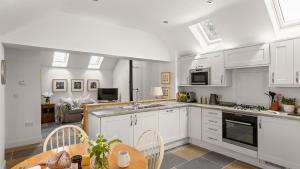 a kitchen with white cabinets and a table and chairs at Applewood in Harome
