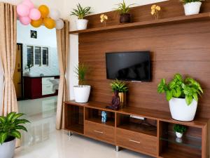 a living room with a television and plants at Neartown Homestay in Kushālnagar
