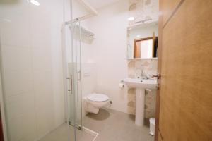 a white bathroom with a toilet and a sink at Sobe B&M Livno in Livno