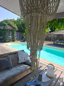 a net over a couch on a deck next to a pool at La Villa du Teich in Le Teich