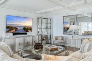 a living room with a couch and a tv on a wall at Three Bedroom Gulffront Condo with Sunset Views in Naples