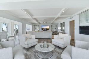 a living room with white furniture and a table at Three Bedroom Gulffront Condo with Sunset Views in Naples