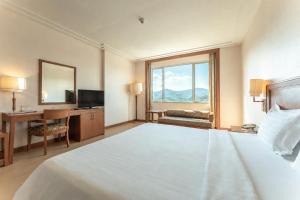 a hotel room with a bed and a desk and a window at Grand Mandarin Betong Hotel in Betong