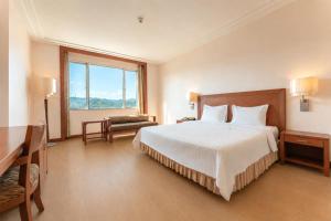 a bedroom with a bed and a desk and a window at Grand Mandarin Betong Hotel in Betong