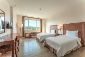 a hotel room with two beds and a desk at Grand Mandarin Betong Hotel in Betong +2 photos