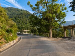 an empty road with trees on the side of a mountain at Anamika Forest View 1RK Near Kempty Falls Mussoorie in Mussoorie