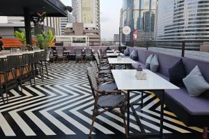 a row of tables and chairs on a rooftop restaurant at Sora Hotel Silom in Bangkok