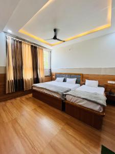 two beds in a room with wooden floors at Hari Kamal Invitation in Mathura