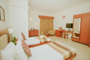 a hotel room with two beds and a living room at Hotel Phoenix Koregaon Park in Pune