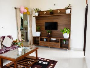 a living room with a television and potted plants at Neartown Homestay in Kushālnagar