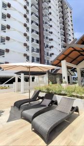 a patio with two chairs and an umbrella and a building at City View Studio Pool - Gym - Caesar Residence in Mactan Island