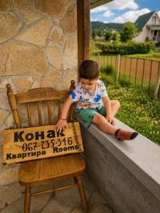 a young boy sitting on a porch next to a chair at Konak in Podgorica +3 photos
