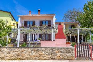a house behind a stone wall with a fence at Apartment Dragica in Valbandon