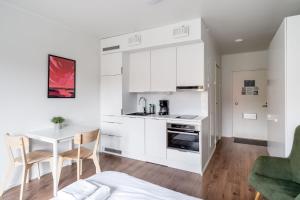 a kitchen with white cabinets and a table and chairs at Hiisi Homes Vantaa Kulomäki in Jokivarsi