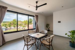 a dining room with a table and chairs and a large window at Saffronstays Crimson Crest in Khopoli