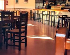 an empty restaurant with wooden chairs and a bar at Hostal de Berge in Berge