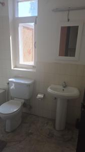 a white bathroom with a toilet and a sink at Winston's Speakeasy & Inn in Pātan
