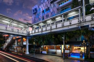a building with a bridge over a street at night at Sora Hotel Silom in Bangkok
