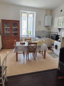a living room with a table and chairs and a kitchen at Maison d'hôtes du Faubourg Charrault Saint Maixent L'Ecole in Saint-Maixent-lʼÉcole