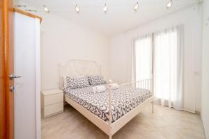 a white bedroom with a bed in a room with windows at A 104 Puntavilla in La Maddalena +12 photos