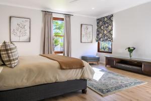 a bedroom with a bed and a dresser and windows at Stony Brook Cottages in Franschhoek