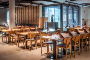 a row of tables and chairs in a room with windows at NaturHotel Snovik in Kamnik